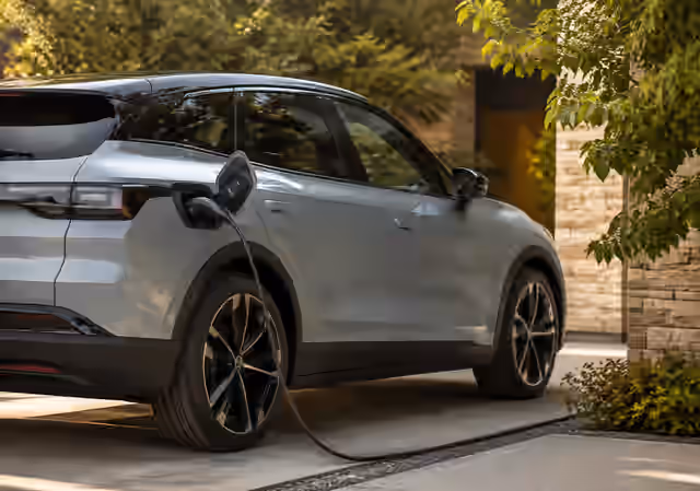 An electric car connected to a charger beside a home